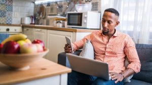 Man using laptop and phone at home