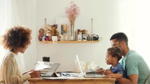 Family using computers at kitchen table.