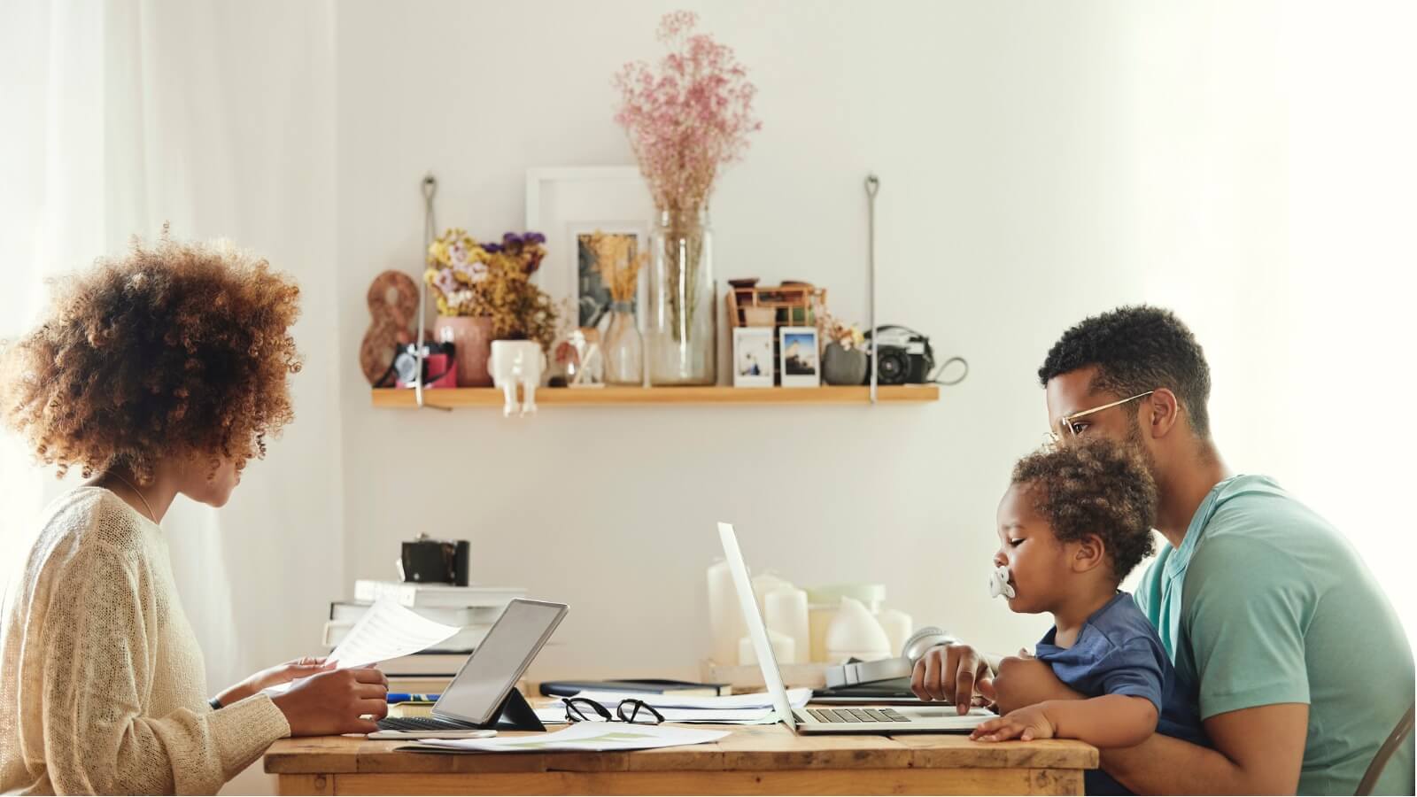 Family using computers at kitchen table.