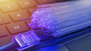 An image of optical fibers and an ethernet cable lying on a keyboard.