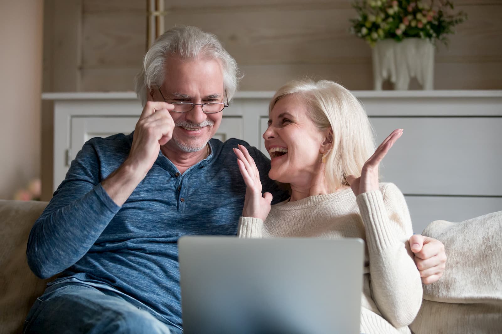 elderly couple sitting at laptop on couch and feeling happy about their internet service