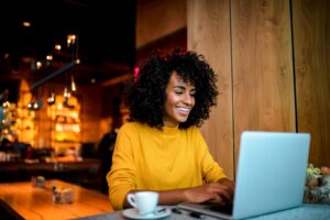 woman sitting at a laptop at a coffee shop and working