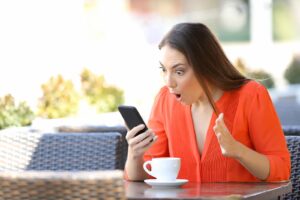 woman expresses amazement while looking at her phone