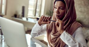 muslim woman sitting at laptop and thinking