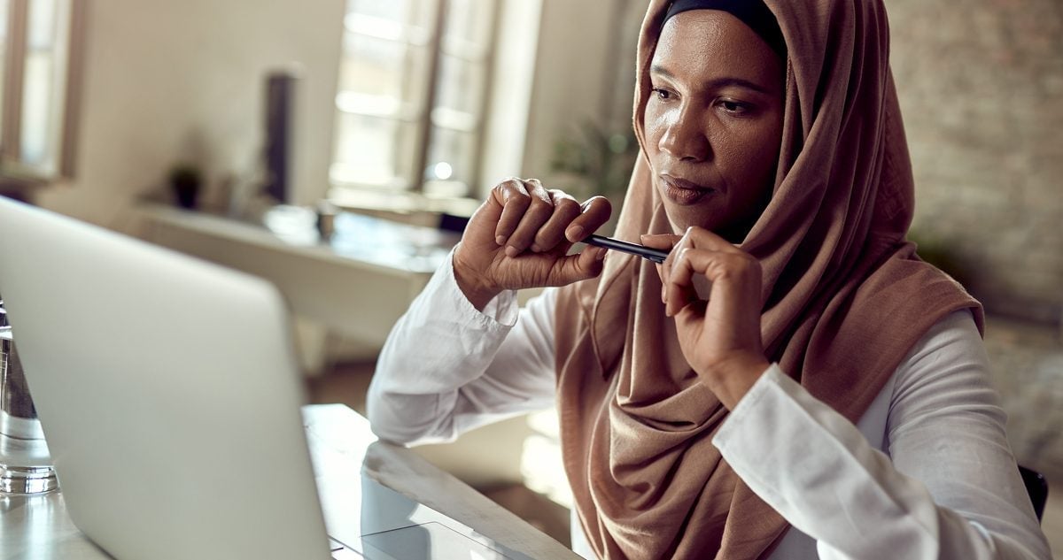 muslim woman sitting at laptop and thinking