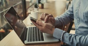 man sitting at his laptop using a phone