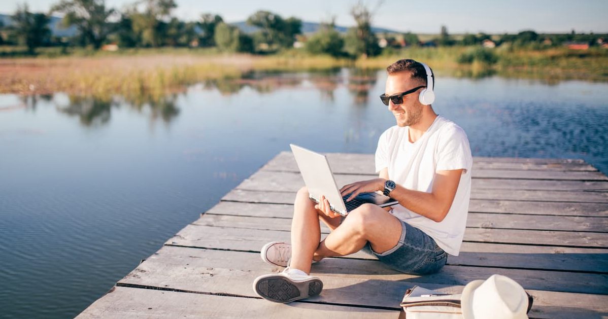 man sitting on pier and using a laptop