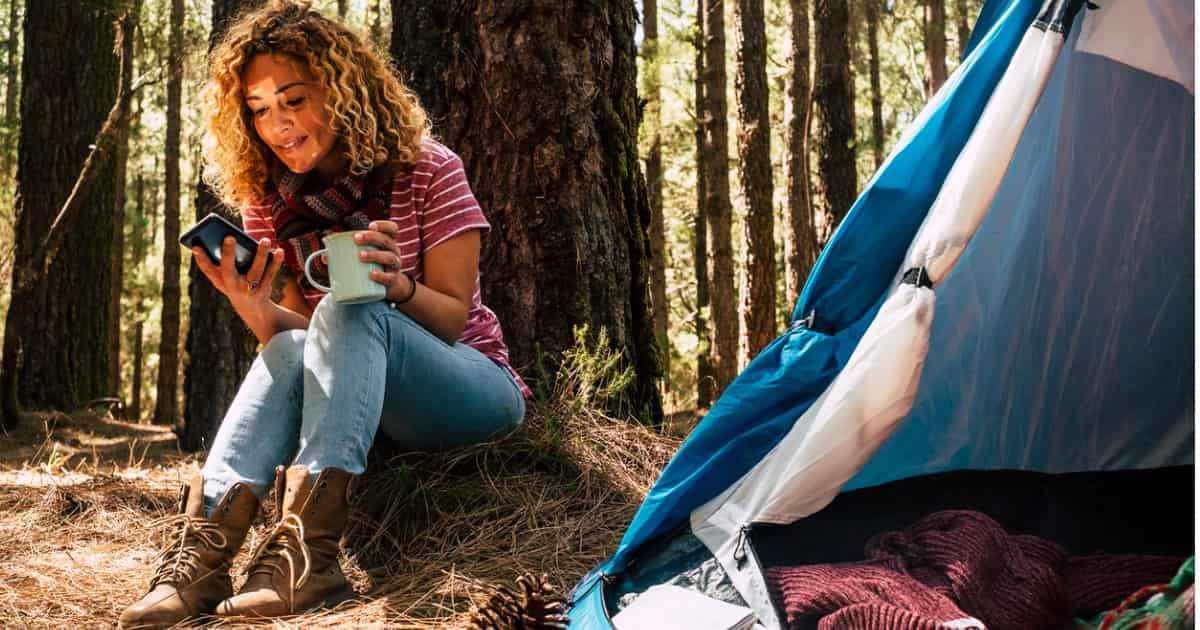 woman using wifi on phone while camping