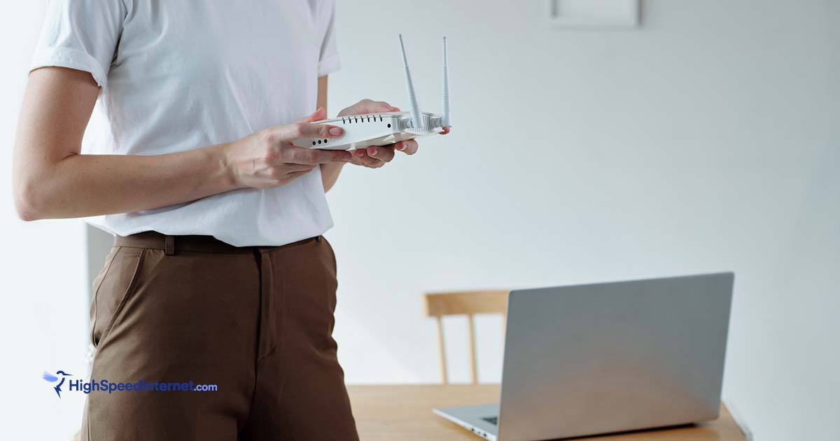 woman setting up internet using router standing next to table with laptop on it