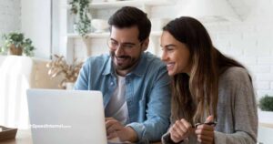 happy couple using laptop in bright kitchen surrounded by plants