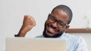 Male holding up triumphant fist looking at computer screen