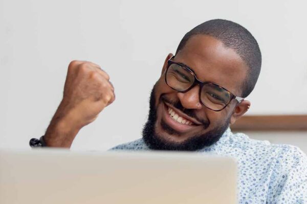 Male holding up triumphant fist looking at computer screen