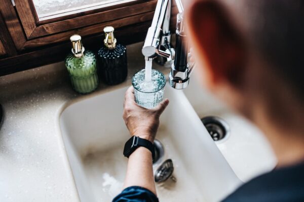 man pouring water into a cup from a faucet