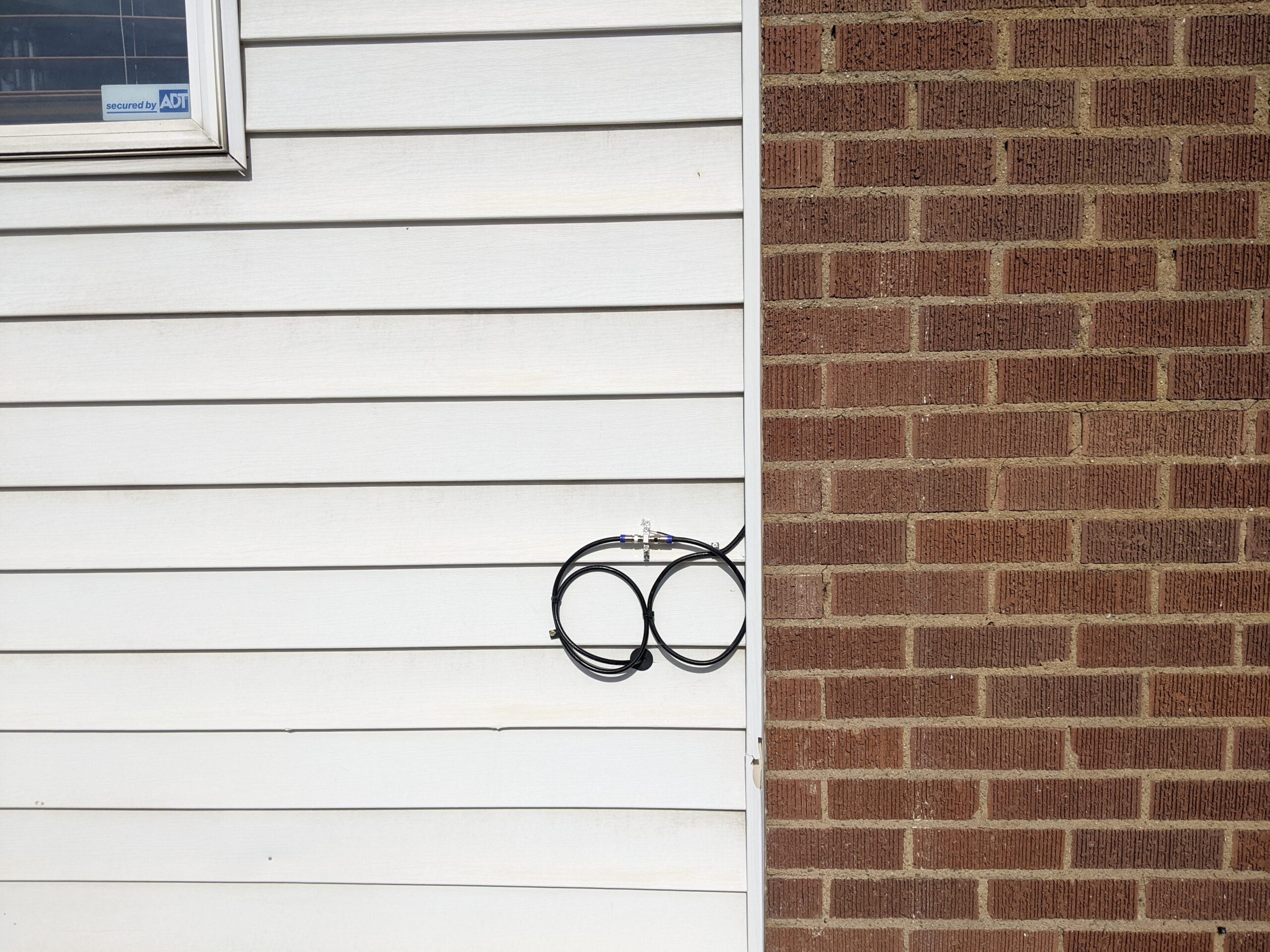 Exterior of house where satellite cable enters the home through a small hole.