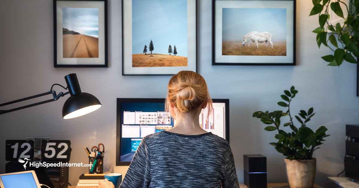 woman using computer at desk with pictures hanging above her on the wall