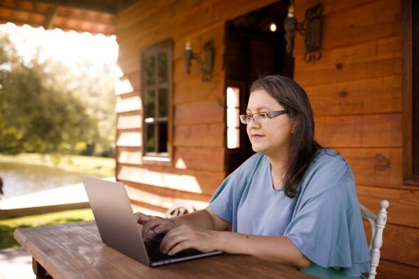 woman sitting at a laptop in a log cabin