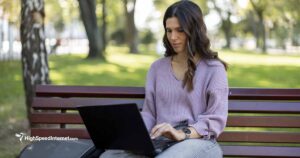 Young woman working on laptop while sitting on park bench One young woman sitting on a bench in the park and using laptop on sunny day 25-29 Years Stock Photo