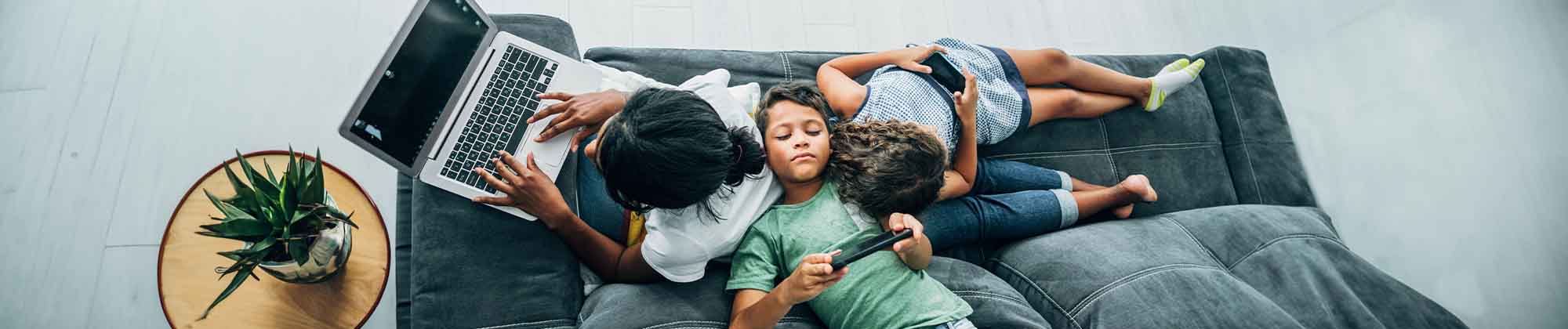 birds eye view of family on couch using multiple devices