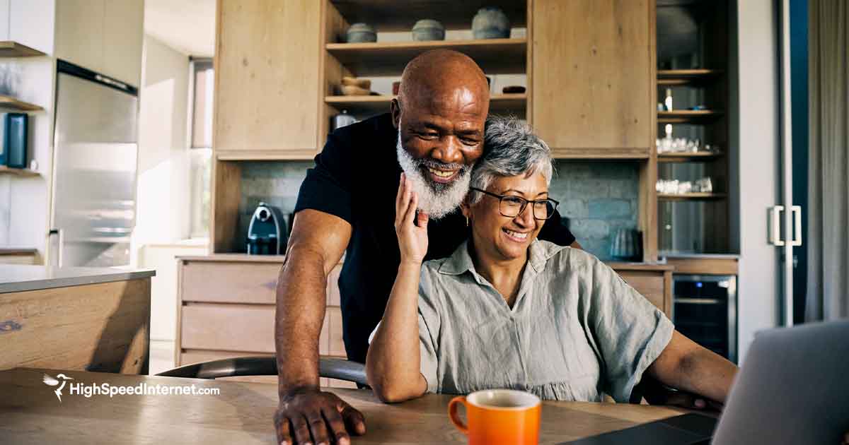 happy african american couple using computer at kitchen table