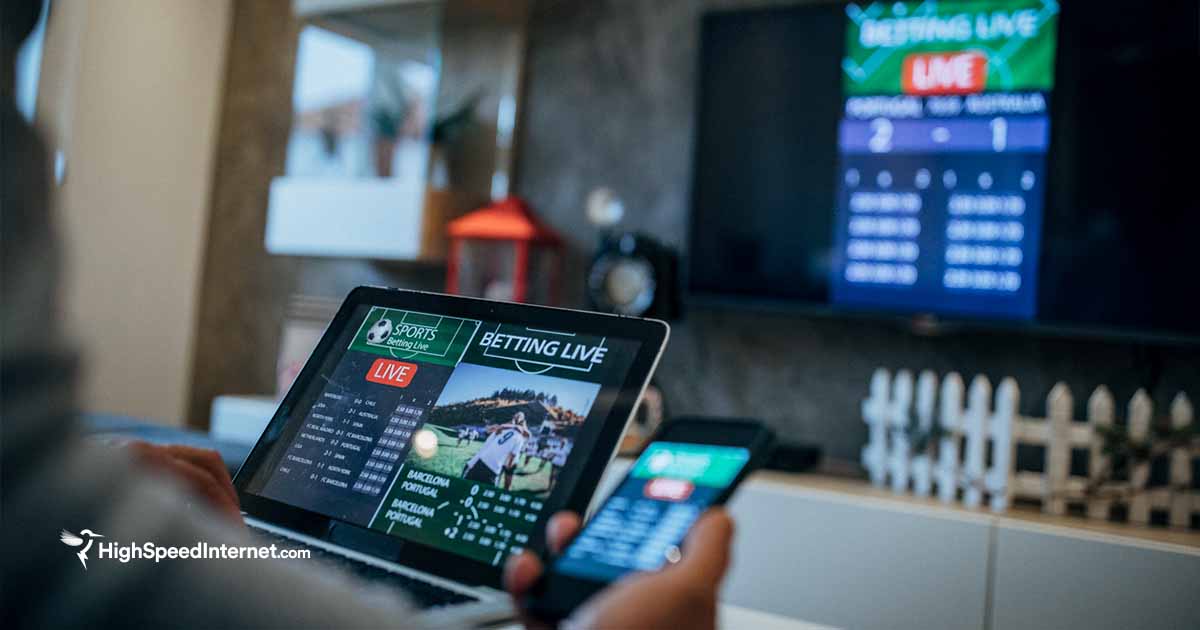 person watching sports on tv while using tablet and phone as well