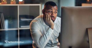 man looking at computer monitor with his face resting on his hand