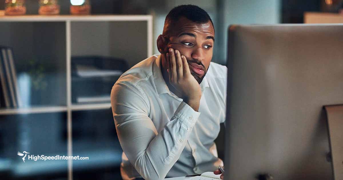 man looking at computer monitor with his face resting on his hand