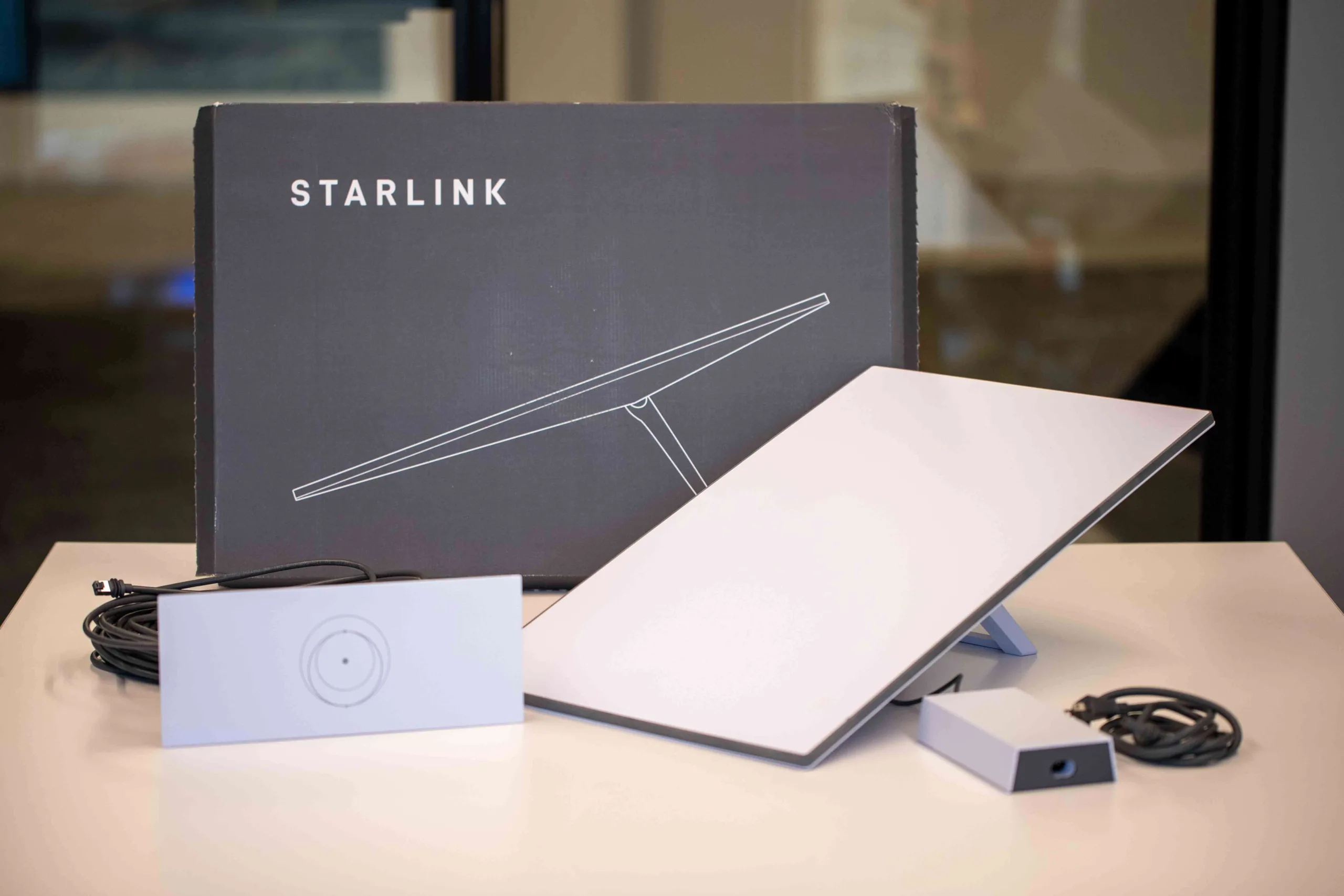 Unboxed Starlink Standard kit, including a receiver dish, Wi-Fi router, power supply, and cables.