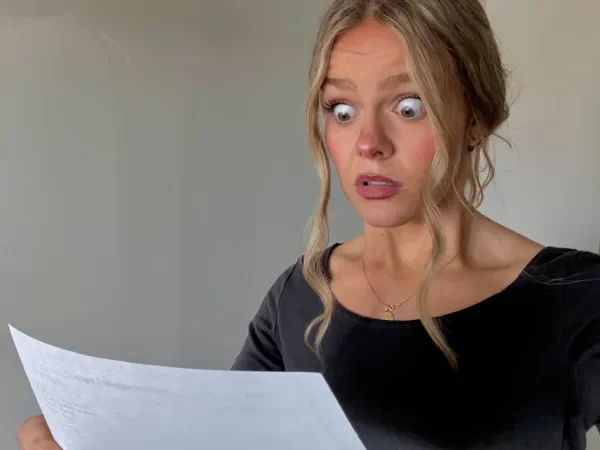 Woman looking at a paper with a shocked expression
